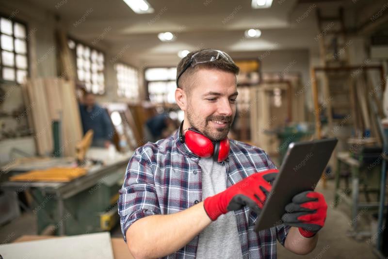A carpenter with a tablet in his workshop